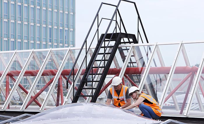 The roof of Almere Centrum railway station. Installers work with dome rooflights and structural glazing systems.