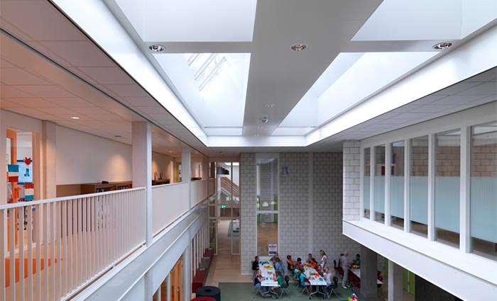 A learning environment with students sat studying beneath rooflight installations that provide natural light 